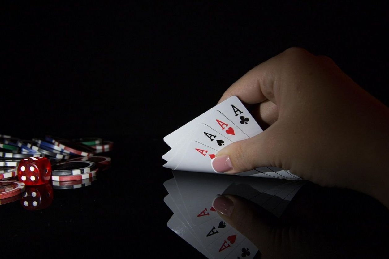 Four aces over a dark game table